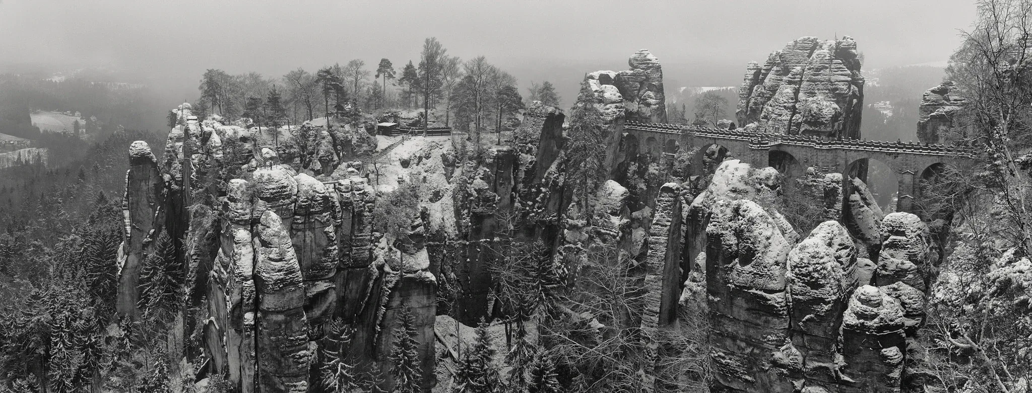 Le pont de Bastei au milieu des rochers enneigés de Suisse saxonne, en noir et blanc.