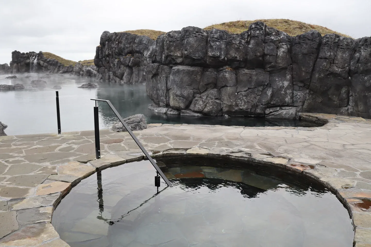 Sky Lagoon’s circular cold plunge pool with a ramp, the lagoon and rocky walls behind it, in August 2021.