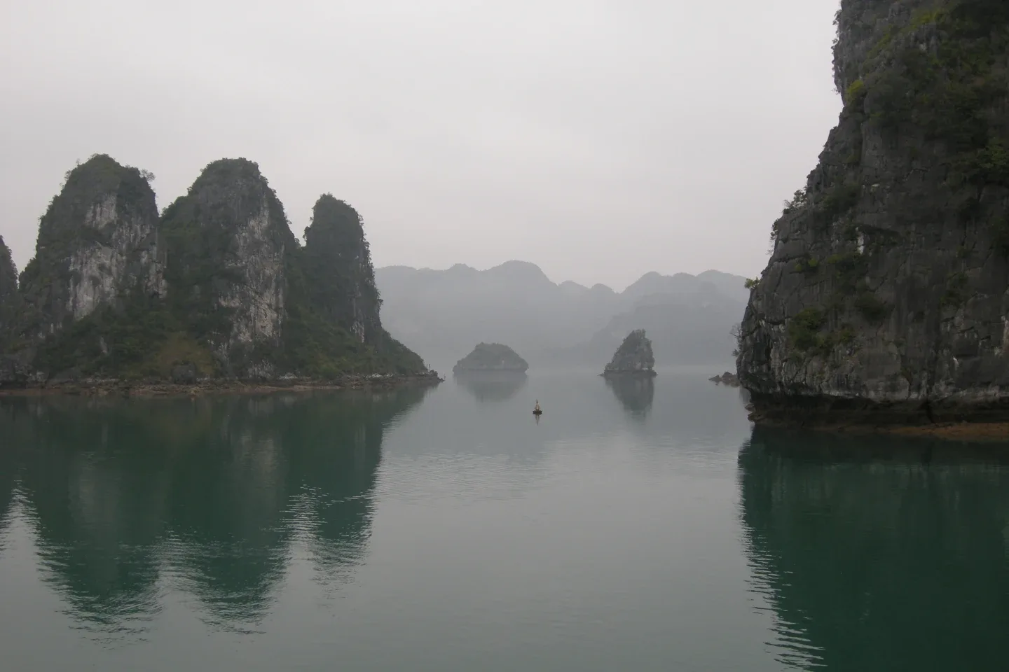 Isole calcaree boscose nelle acque calme e nebbiose della baia di Ha Long.