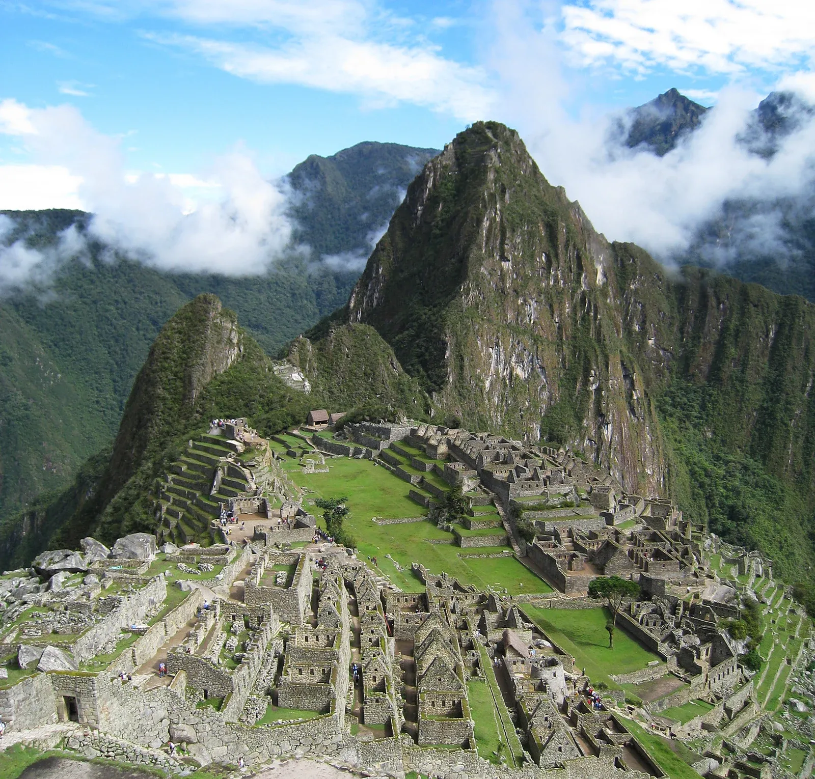 Oversiktsbilde av Machu Picchu med Huayna Picchu og skyer over fjellsidene.