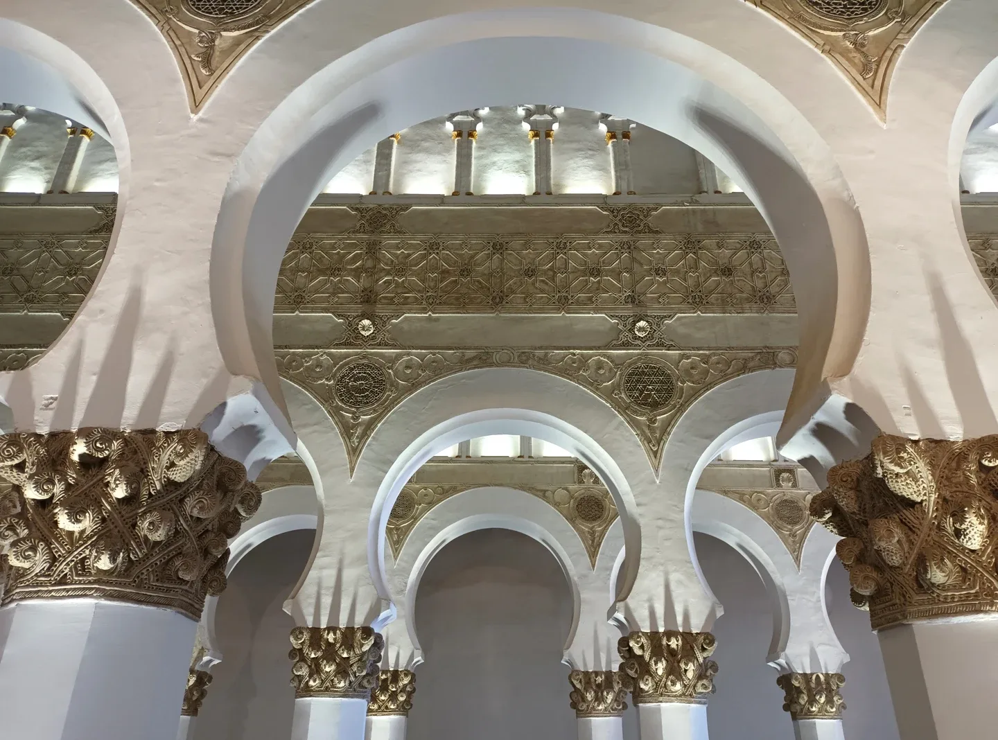 File di archi bianchi e capitelli scolpiti all’interno di Santa María la Blanca, a Toledo.