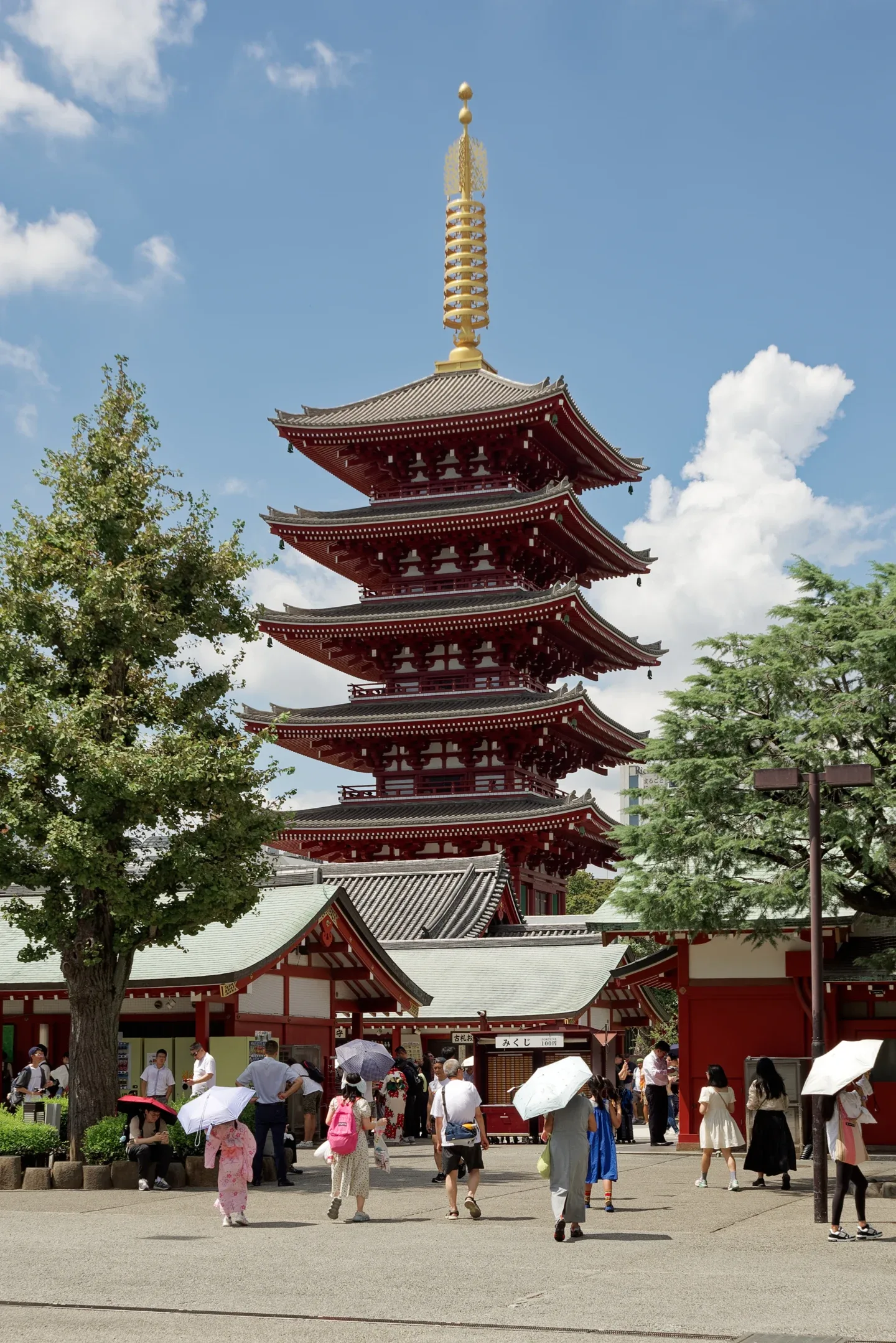 The five-tier red pagoda at Senso-ji in Asakusa, rising above visitors and temple buildings.